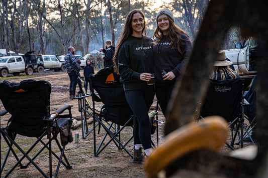 Offmain girls wearing their black hoodie, enjoying their drinks in a campsite.