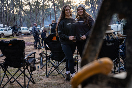 Offmain girls wearing their black hoodie, enjoying their drinks in a campsite. 